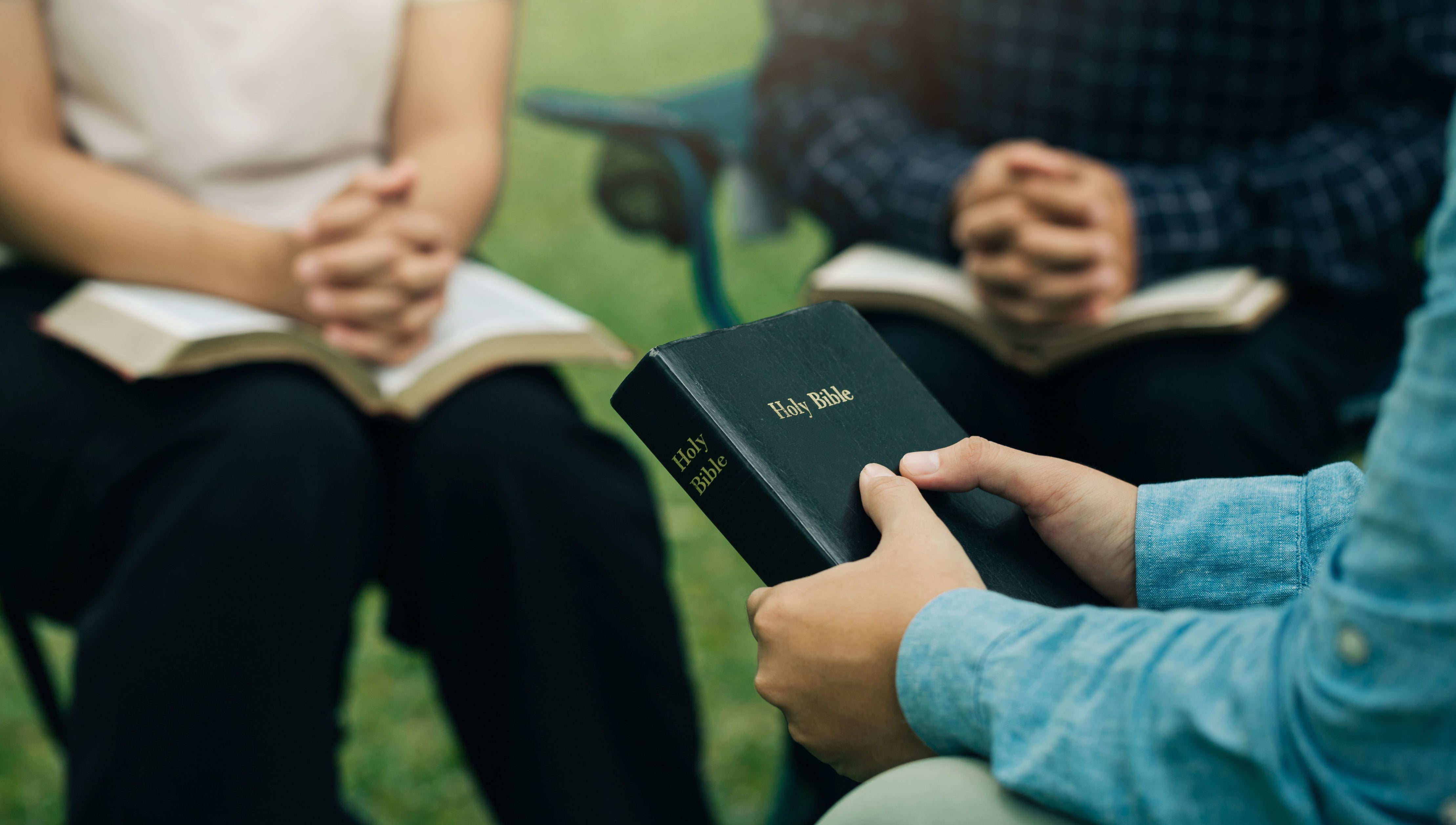 Man holding bible with group of christians praying