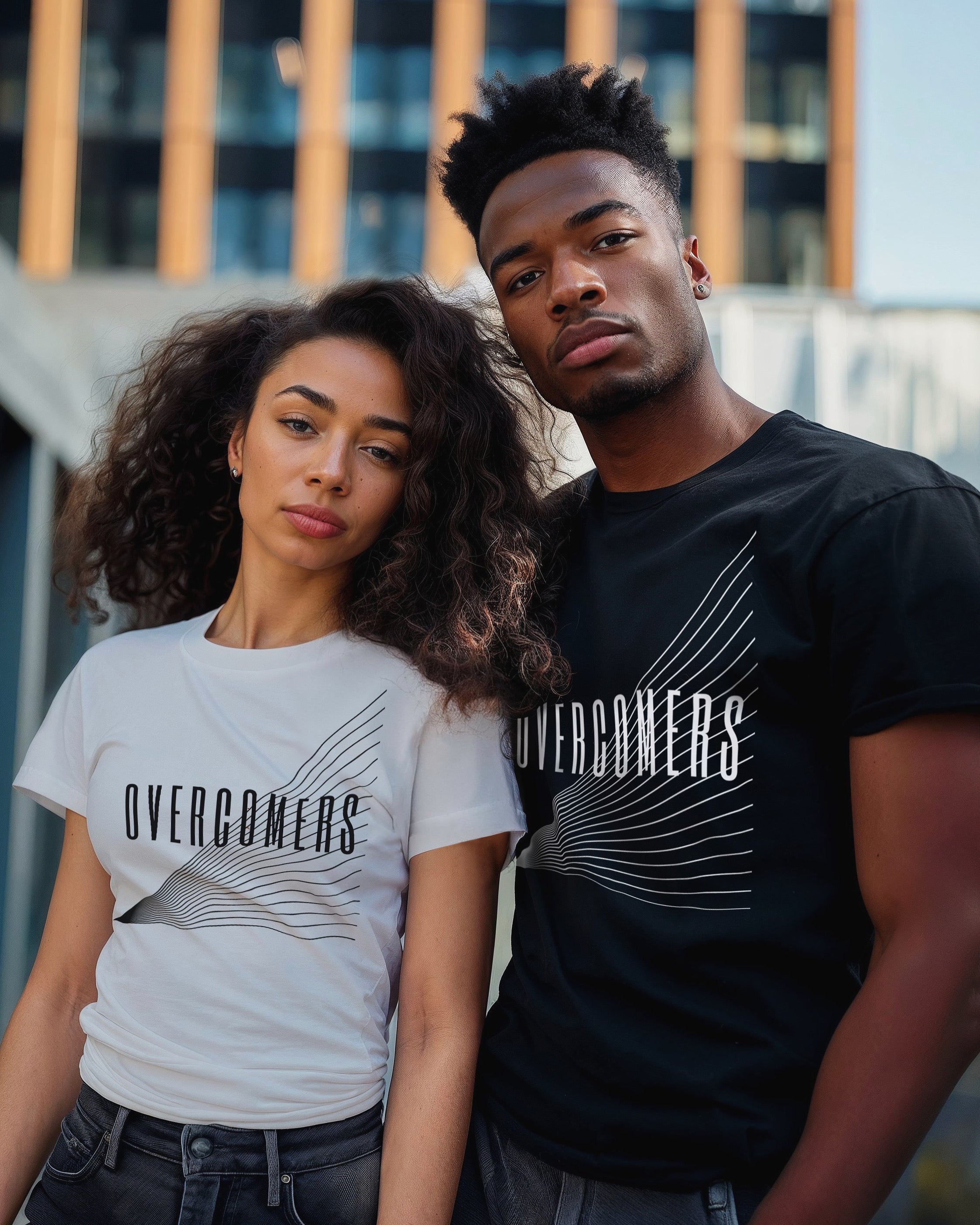 Man wearing black 'Overcomers' collection t-shirt standing next to woman wearing white 'Overcomers' collection t-shirt 